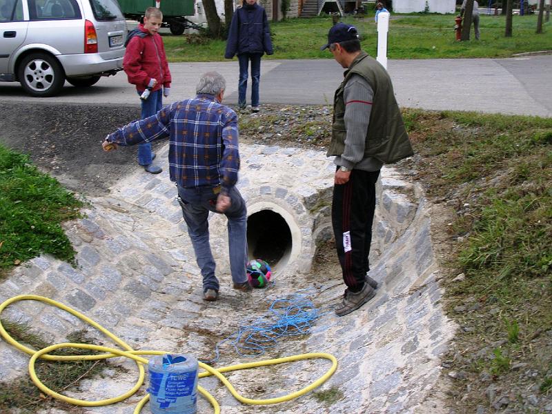 Aufbau_Kicker.JPG - Unkonventielle Art, im Durchlass den Wasserschlauch zu legen. Andy probiert's mit einem Ball (mit Schnur) und einem kräftigen Schuß. Idee nicht schlecht, Ausführung allerdings erfolglos....