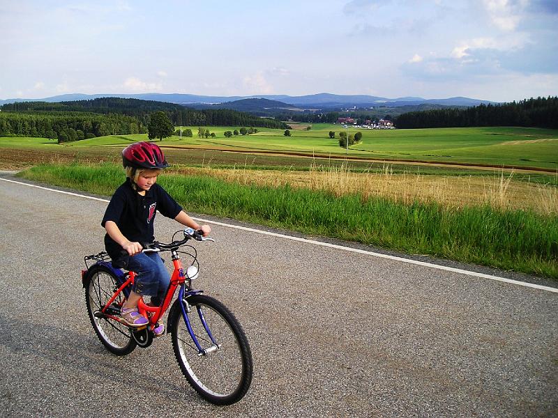 Anja.JPG - Sogar die Sonne ließ sich wieder sehen, Anja kann wieder kurzärmelig fahren (im Hintergund Spielhof).